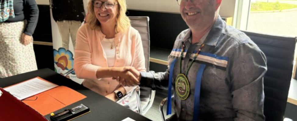 SGEI CEO Brent Tookenay and Confederation College Presient Michelle Salo shake hands while sitting together at a table